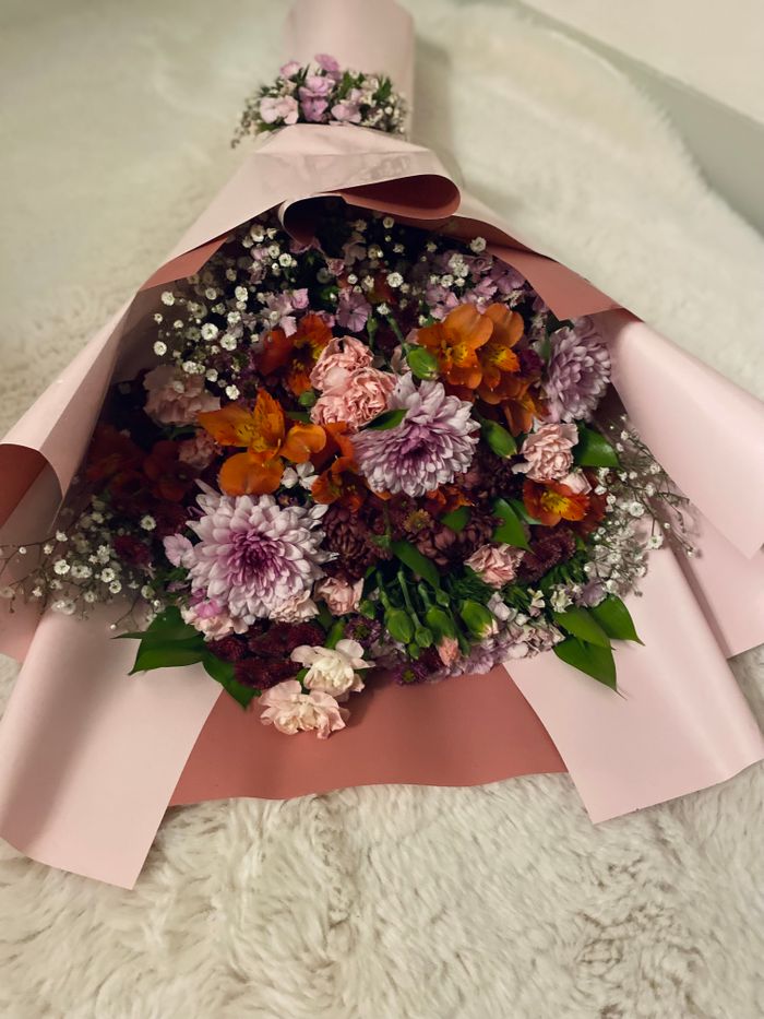 Beautiful bouquet featuring chrysanthemums, baby's breath, and lush greenery elegantly wrapped in pink.