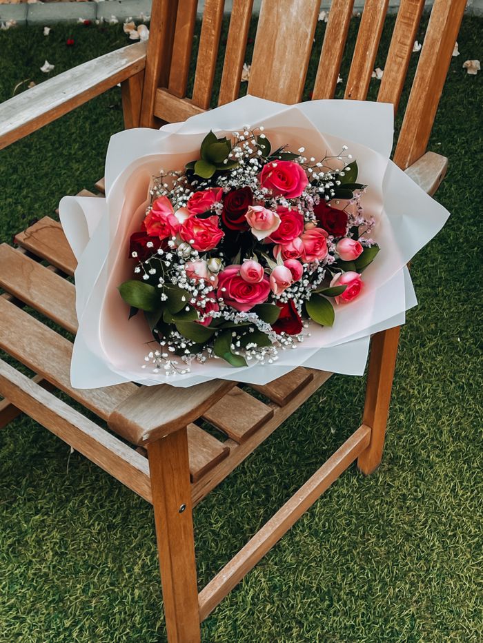Stunning bouquet of pink and red roses with baby's breath on a wooden chair.