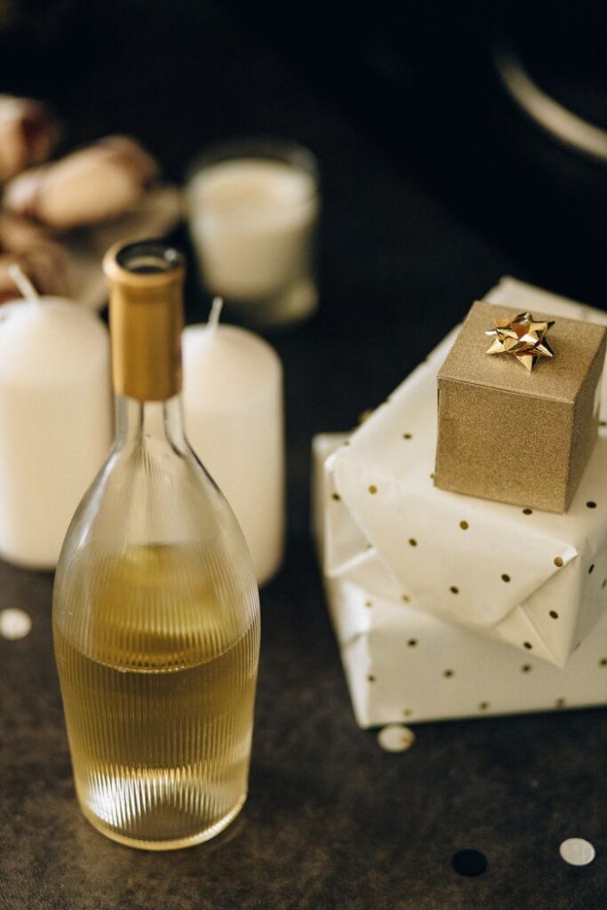 Sophisticated scene of wine bottle and elegantly wrapped gifts surrounded by candles.